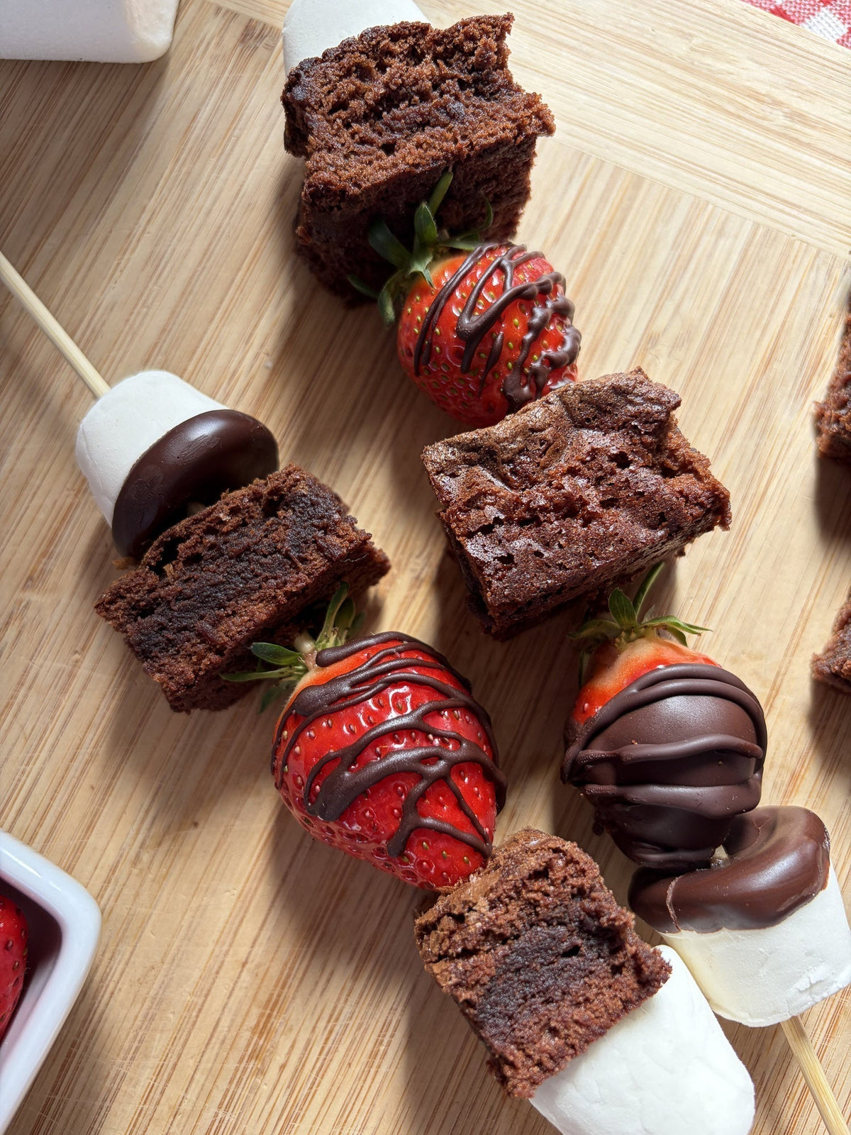 Skewers of brownie squares, marshmallows and chocolate-dipped strawberries.
